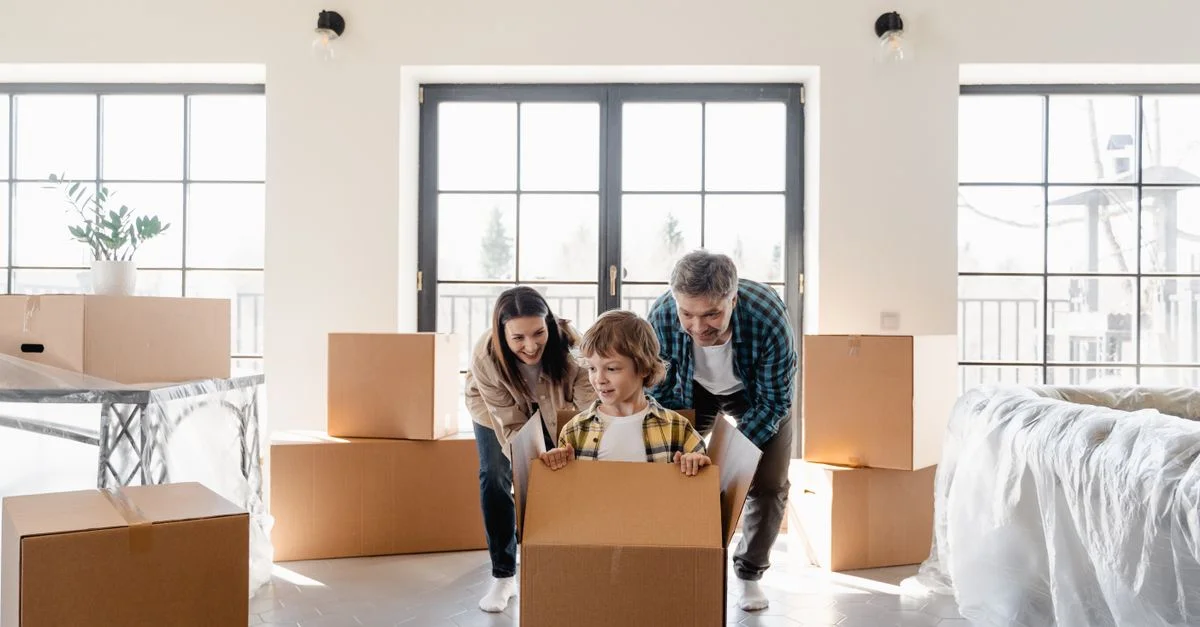 Une famille joyeuse déballe des cartons de déménagement dans leur nouvelle maison, créant des souvenirs joyeux.