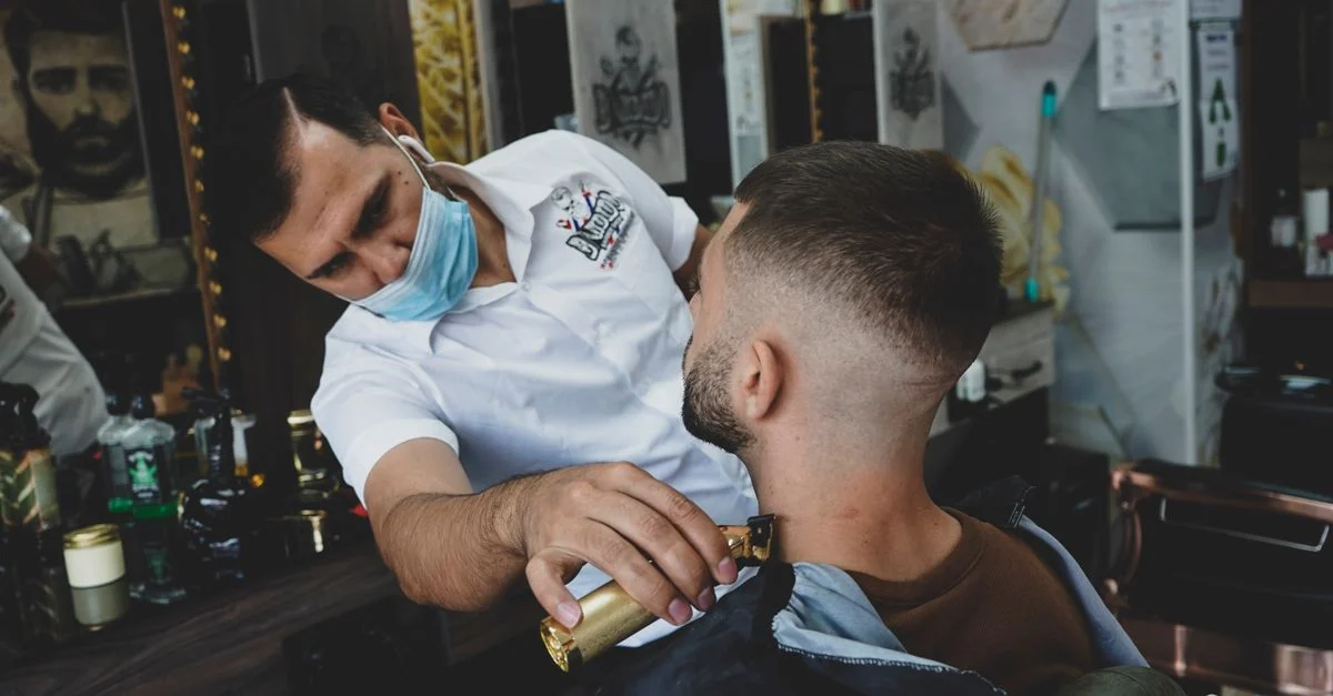 Barbier effectuant un rasage précis avec un rasoir sur un client dans un cadre de barber shop moderne.