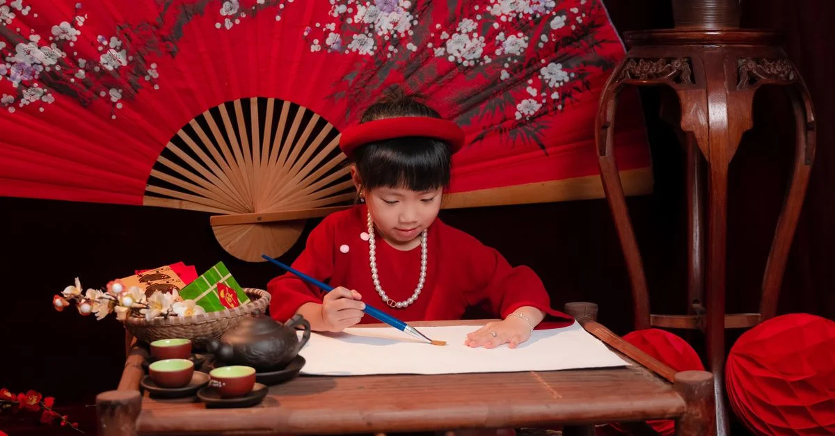 Un enfant en vêtements traditionnels vibrants, peignant avec un pinceau, entouré de décor culturel.
