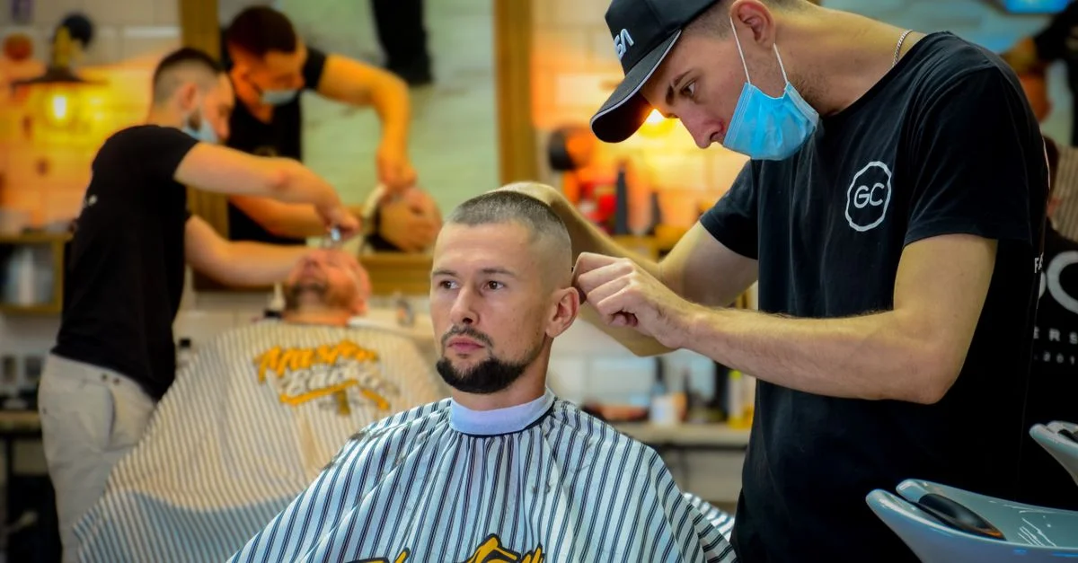 Coiffeur masculin coupant habilement les cheveux d'un homme dans un salon de coiffure contemporain.
