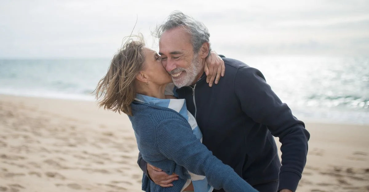 Un couple mature profitant d'un moment romantique sur une plage portugaise, symbolisant l'amour et la complicité.